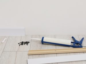 Individual demonstrating how to reseal a shower by applying paint to a bathroom wall with a blue and white roller, showcasing a crucial step in the shower resealing process.