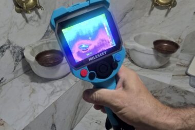 Thermal imaging camera detecting bathroom leak around marble basin and tiled wall