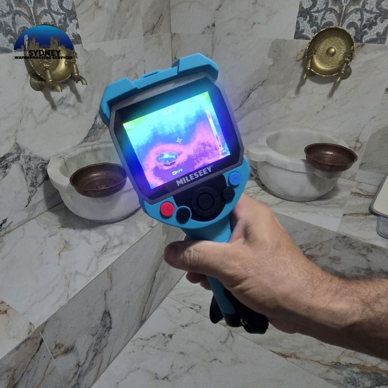 Thermal imaging camera detecting bathroom leak around marble basin and tiled wall